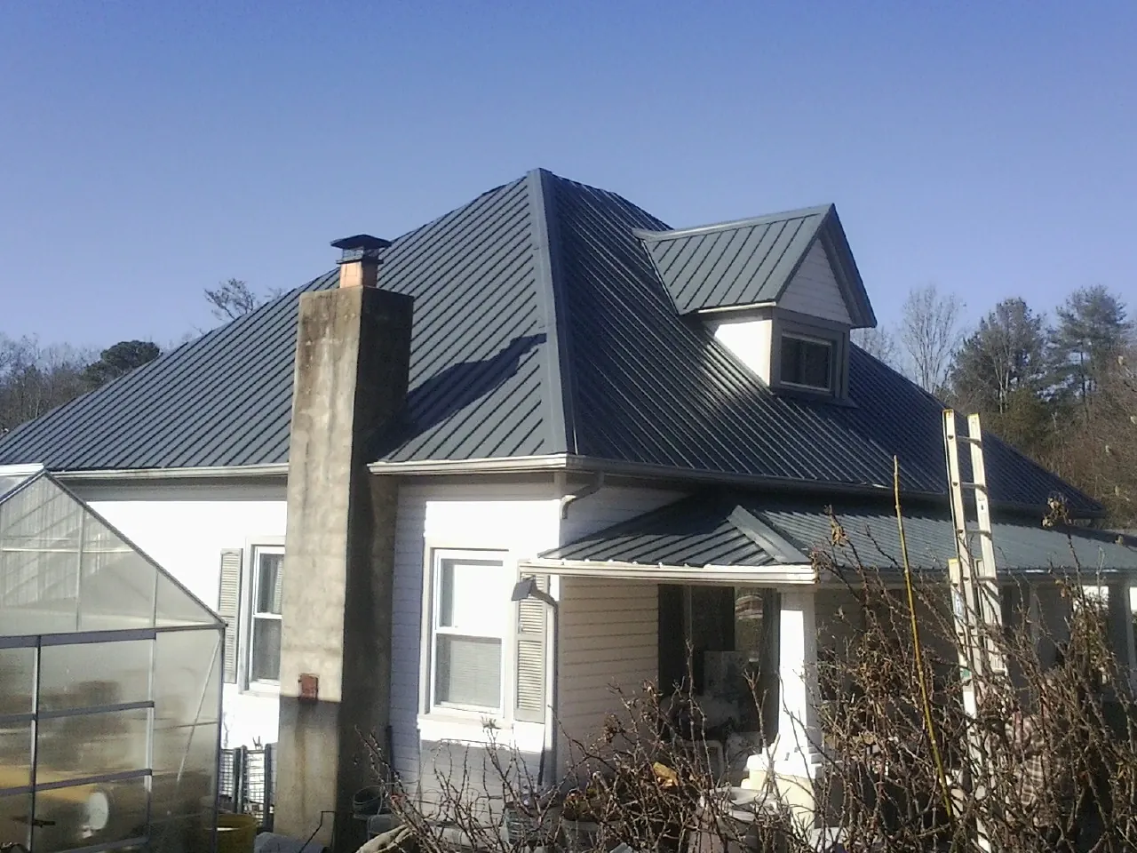 Dark blue standing seam metal roof on a white farmhouse with dormer — Slate & Tile Roof Repair by Roofing Brothers in Hebo