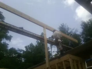 Carpenter setting a ridge beam over a new addition frame — Ice Dam Removal by Roofing Brothers in Hebo