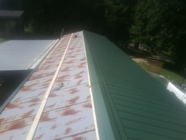 Old rusted panels beside newly installed green metal roofing — Wind Damage Roof Repair by Roofing Brothers in Hebo