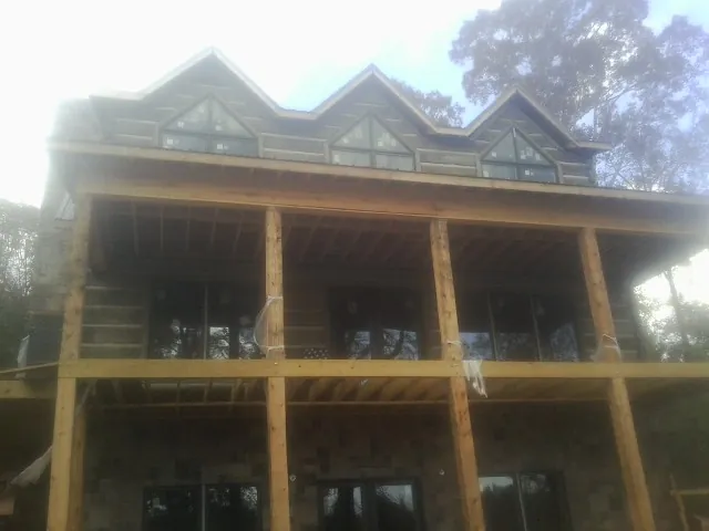 Dormers and porch framing on a large log home under construction — Roof Coating work by our crew in Hebo