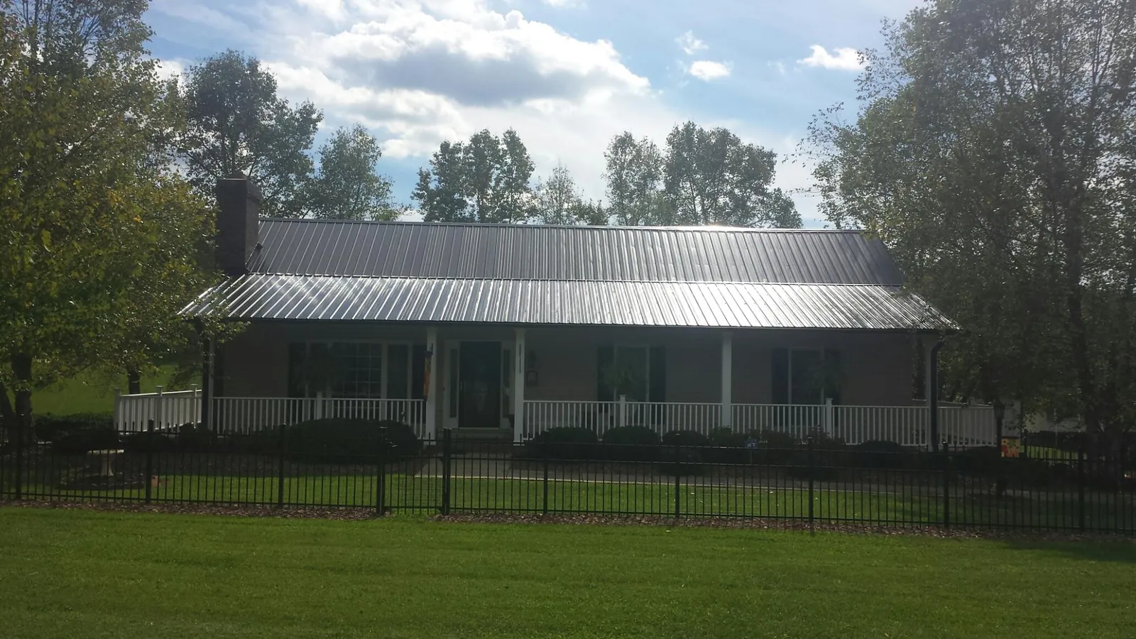 Gray metal roof on a brick ranch with a full width front porch — Gutter Guard Installation work by our crew in Hebo