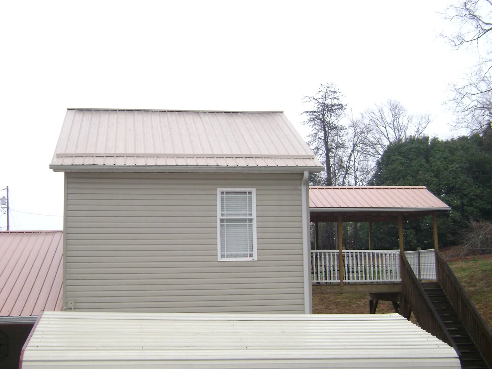 Tan metal roofs on a two story addition and attached porch, from a Roof Replacement job in Hebo