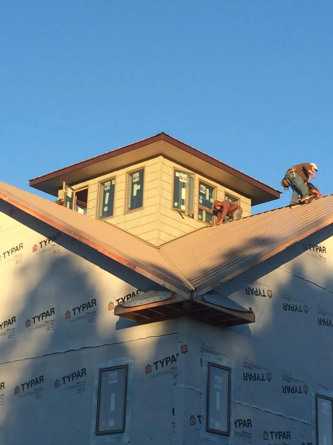 Roofers working around a rooftop cupola on a new metal roof at sunset — Roof Waterproofing in Hebo by Roofing Brothers